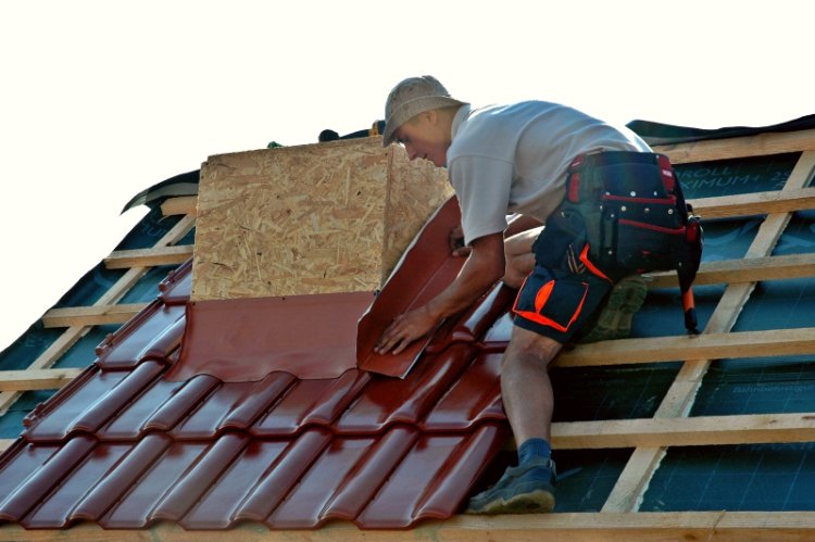 Pracownik wykonuje obróbki blacharskie na dachu